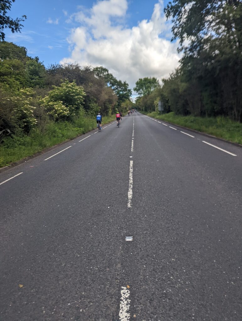 Photo of Epping New Road with two cyclists (and the existing very narrow cycle lane)
