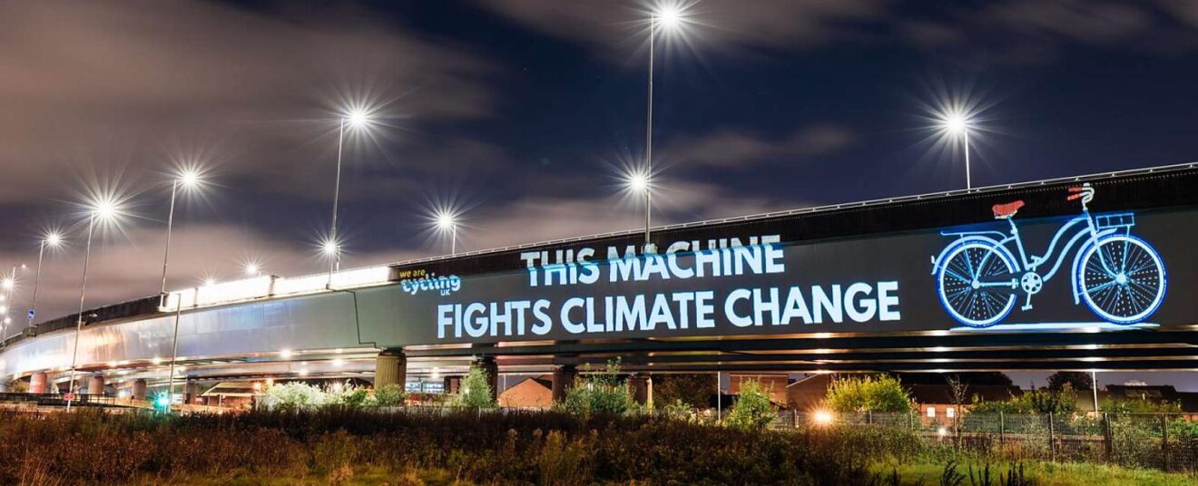 Photo (projection on building of bicycle with caption) "This machine fights climate change"